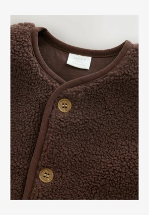 Chaqueta de forro polar marrón con una textura suave, con escote en V, ribete marrón y dos botones redondos para el cierre. La etiqueta dice "NEXT baby."
