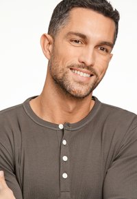 Donkergrijze henley shirt van zachte stof, met een ronde halslijn, subtiele stiksels en witte knopen langs de voorbies.