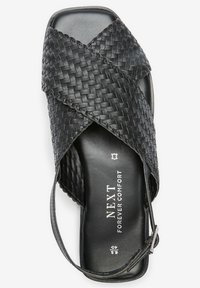 Sandalia de cuero tejida negra con diseño de tiras cruzadas, plantilla acolchada y correa ajustable en el tobillo. Presenta la marca en la plantilla.