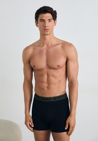 Fekete boxer alsónadrág, rugalmas anyagból, zöld derékpánttal, amelyen a "BJÖRN BORG" márkaneve szerepel. Sima textúra, testhez simuló fazon.