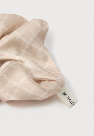 Coletero de seda en beige suave con un sutil patrón geométrico. Presenta una etiqueta con la inscripción "BY MALE" en texto negro. Textura suave y forma flexible.