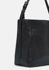 Czarna skórzana torba typu bucket z regulowanym paskiem na ramię i widocznymi detalami przeszycia na białym tle.