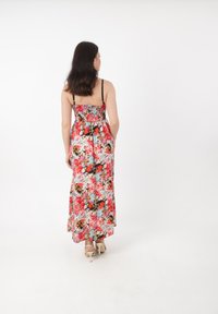 Blomstret maxikjole med smocket bodice, prydet med et livligt mønster af røde, pink og blå blomster, med tynde sorte stropper og et svævende design.