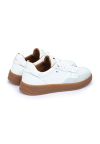 Sneaker bianchi in pelle con suole e dettagli in gomma color tan. Presentano perforazioni testurizzate, lacci e un logo sul tallone e sul lato.