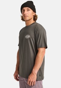 Dark gray cotton t-shirt with short sleeves and a crew neck, featuring a small circular mountain logo on the left chest.