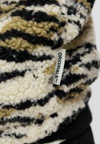 Suéter de borreguito con un patrón de rayas en crema y negro, con una etiqueta visible etiquetada como "ORIGINALS™" en la costura.
