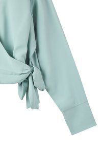 Blusa verde menta con maniche lunghe, caratterizzata da un dettaglio a nodo legato in vita e da una texture di tessuto liscia e leggera.
