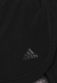 Černé sportovní šortky vyrobené z hladké tkaniny s křivkovým designem, zdobené nenápadným černým logem Adidas a kontrastním prošíváním.