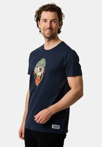 Navyblå bomullströja med en grafik av en hund i en grön mössa och hörlurar, med en orange detalj på bröstet och en etikett på fållen.