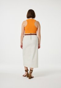 Orange ribbed tank top, white midi skirt with a brown studded belt, and brown leopard print high-heeled sandals. Textured and fitted design.