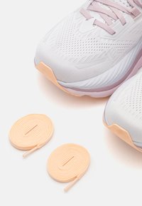 Baskets de course légères en mesh blanc avec des accents lavande, dotées d'une semelle rembourrée. Comprend des lacets de couleur pêche.