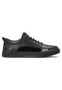Zapatillas negras con parte superior de cuero suave, acentos brillantes en contraste, cordones redondos y suela de goma plana. Diseño limpio y minimalista.