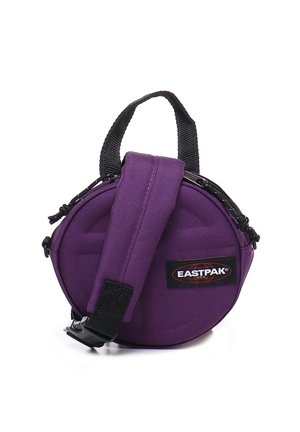 Bolso redondo morado hecho de tela duradera. Cuenta con un asa superior y una correa ajustable, con un cierre con cremallera y un parche de logo.