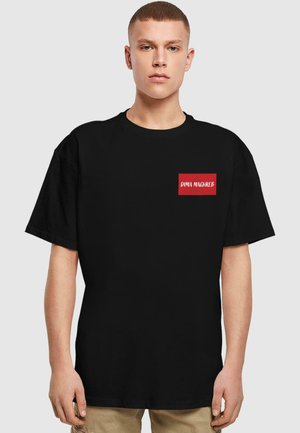 Sort bomuld t-shirt med afslappet pasform, prydet med en rød rektangulær lapp med teksten "DIMA MAGHREB" i hvid, korte ærmer.