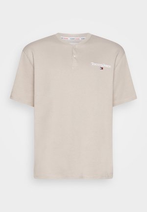 Beżowa koszula Tommy Jeans z krótkim rękawem, z plisą na dwa guziki i małym logo na lewej piersi.