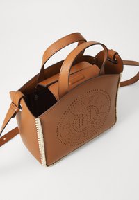 Borsa a mano in pelle marrone con design perforato, dotata di manici superiori doppi, una tracolla e cuciture intrecciate lungo i bordi.