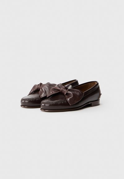 Mocasini din piele maro, cu un detaliu decorativ sub formă de fundă în față. Prezintă accente cusute și un design cu tocul jos pentru confort.