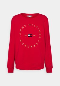Rode sweatshirt met lange mouwen, voorzien van een gouden cirkelvormige tekst "Tommy Hilfiger", een centraal logo, "EST. 1985" en geribbelde manchetten en zoom.