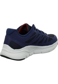 Baskets de sport bleu marine avec une tige en maille texturée, accents noirs et une semelle blanche avec des bandes pour une meilleure adhérence. Doublure intérieure rouge.