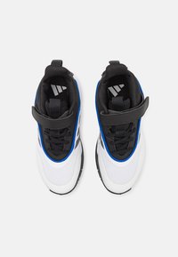 Scarpe sportive in bianco e nero con dettagli blu, materiale in rete, forma arrotondata, dotate di una fascia e lacci nella parte superiore. Suola texturizzata.