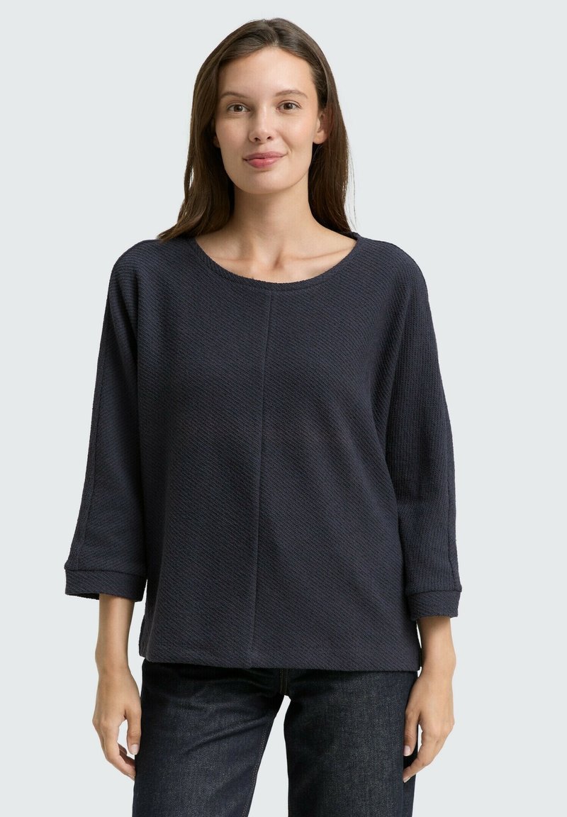 Donker marineblauw gebreid shirt met een ronde halslijn, driekwartmouwen en structuurstof. Beschikt over een ontspannen pasvorm en een eenvoudig ontwerp.