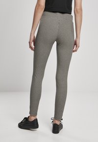 Fekete-fehér kockás leggings magas derekú és slim fit fazonnal. Fekete sportcipővel viselve, amely kiemeli a texturált, mintás dizájnt.