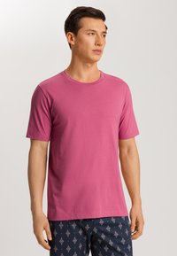 T-shirt in cotone rosa con colletto rotondo e maniche corte, abbinato a pantaloni corti scuri con un motivo a diamante. Vestibilità semplice e casual.