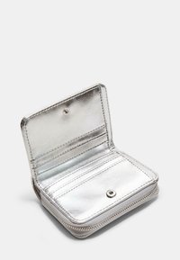 Srebrny metaliczny portfel z zapięciem na zamek, o gładkiej teksturze, z wieloma przegródkami na karty i z zatrzaskiem dla bezpiecznego zamknięcia.