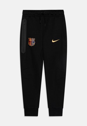 Pantaloni della tuta neri con vita elastica, tasca laterale con zip, badge FCB e logo Nike in oro. Presenta gambe affusolate e una morbida texture del tessuto.