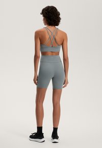 Ljusgrå atletisk set bestående av enkort topp med korsade remmar och högmidjade shorts. Mjukt, stretchigt tyg för komfort.