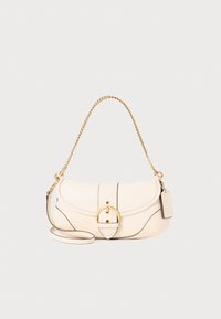 Cream leather handbag with a gold chain strap, rounded shape, and flap closure featuring a circular buckle. Black accent stitching and tag included.