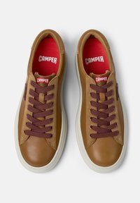 Bruna sneakers i läder med en slät yta, rund tå, bordeauxfärgade snören och en röd innersula med "CAMPER"-logotypen. Vit gummisula.