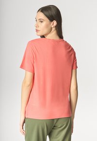 T-shirt corallo a maniche corte realizzato in morbido tessuto leggero con un semplice collo a giro, presenta una vestibilità rilassata e cuciture pulite.