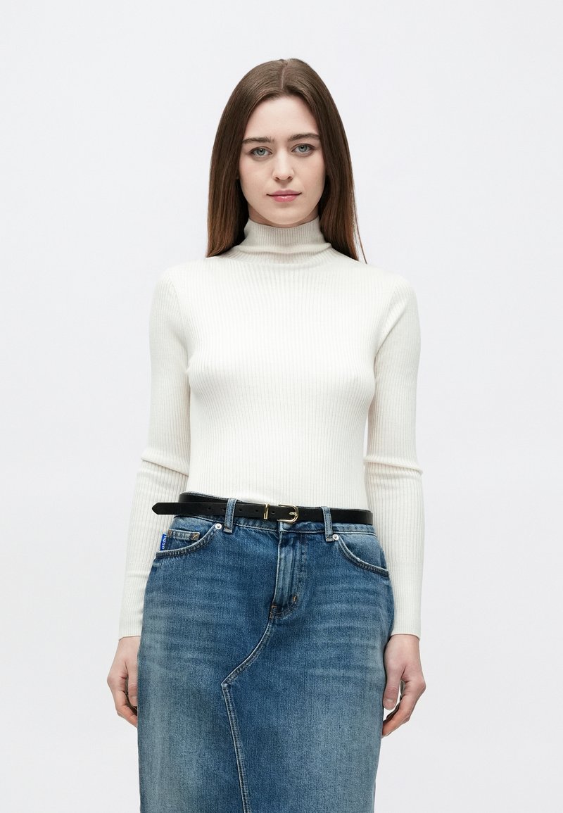 Biały prążkowany sweter z golfem w połączeniu z niebieską spódnicą jeansową. Spódnica ma przedni rozcięcie oraz czarny pasek ze złotą sprzączką.