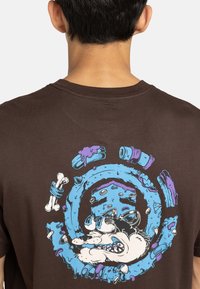 Bruine katoen t-shirt met een kleurrijke grafische print van een gestileerd dier en ronde elementen op de achterkant. Korte mouwen, ronde hals.