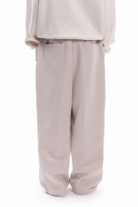 Μπεζ, άνετο παντελόνι από απαλό ύφασμα με λεία υφή, που διαθέτει δύο πλαϊνές τσέπες και χαλαρή σιλουέτα.