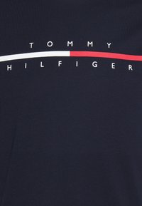 Camiseta de algodón azul marino con rayas horizontales blancas y rojas, con "TOMMY HILFIGER" impreso en letras blancas grandes en el pecho.