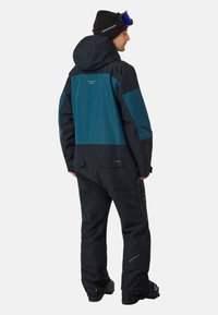 Zwarte en groene skibroek met een capuchon, voorzien van een ritszak en versterkte naden. Glad textuur, ontworpen voor wintersport.