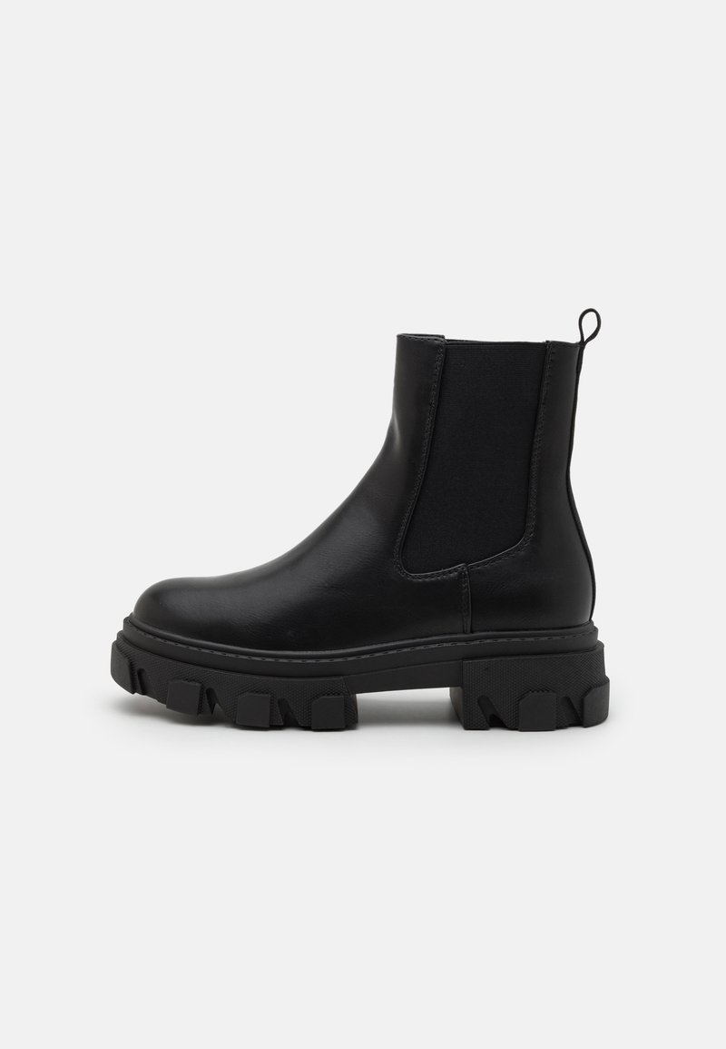 Botas de cano curto em pele preta com painéis laterais elásticos, sola de borracha robusta e alça de puxar. Apresentam uma textura suave e um padrão de ranhura definido.