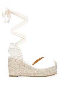 Sandalia de cuña blanca de espadrille con una suela de yute trenzado, que presenta una correa en el tobillo texturizada que se ata por encima del tobillo.