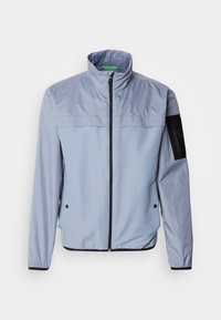Light blue, long-sleeve jacket with a high collar, zip front, and black accents. Features a pocket on the left sleeve and elastic cuffs.