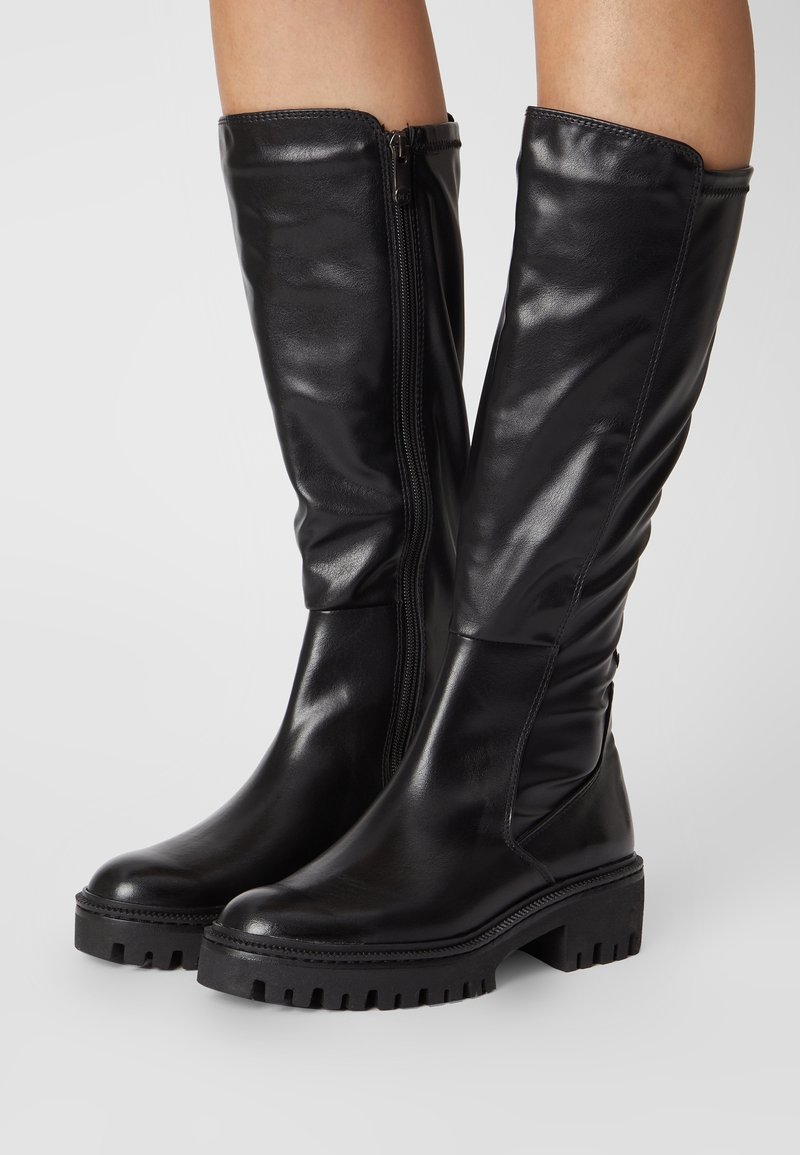 Bottes noires hauteur genou avec une finition en cuir brillant, dotées d'une fermeture éclair sur le côté et d'une semelle noire épaisse et texturée.