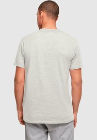 Lys grå bomulds T-shirt med kortærmer og rund hals, der har en glat tekstur og en lige kant. Bagfra ses et enkelt design.