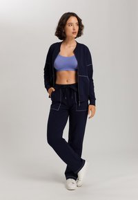 Navy modrá bomber bunda na zip s světlým prošíváním, doplněná modrým sportovním brá a námořnickými joggery. Celý vzhled doplňují bílé tenisky.