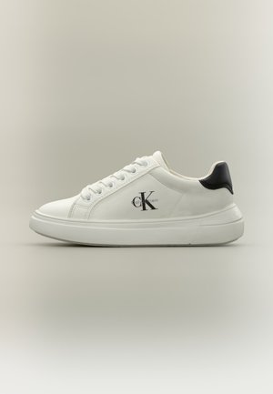 Baskets basses blanches avec lacets blancs, languette de talon noire et logo Calvin Klein sur le côté, vues de l'extérieur.