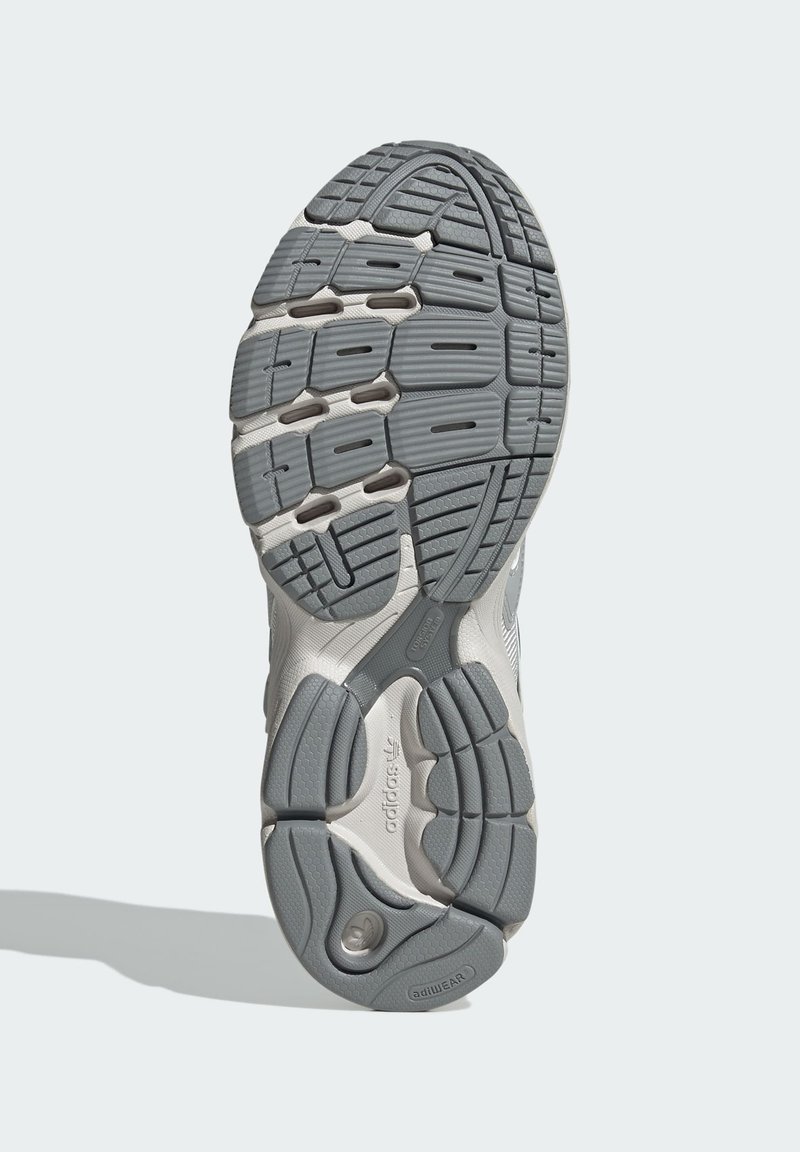 Suela de zapatilla deportiva con un diseño de goma texturizada en gris y blanco. Incluye ranuras para tracción y un logo de adiWEAR.