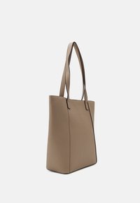 Hnědá taška na rameno s hladkým povrchem, se dvěma dlouhými uchy a kontrastním černým prošíváním podél okrajů. Vertikálně strukturovaný design.
