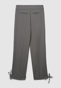 Pantaloni grigi su misura con tasche a welt posteriori e legacci regolabili sui polsini, mostrati distesi su uno sfondo bianco.