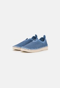 Blaue Slipper mit einer strukturierten Oberseite und Ausschnitten, einer runden Zehenpartie und einer kontrastierenden beige Gummisohle mit Zickzackmuster.