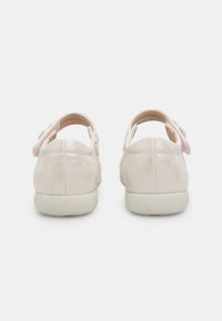 Różowe skórzane buty o gładkiej fakturze, zaokrąglonym kształcie i z paskiem z tyłu. Charakteryzują się dekoracyjnym różowym akcentem na pasku.